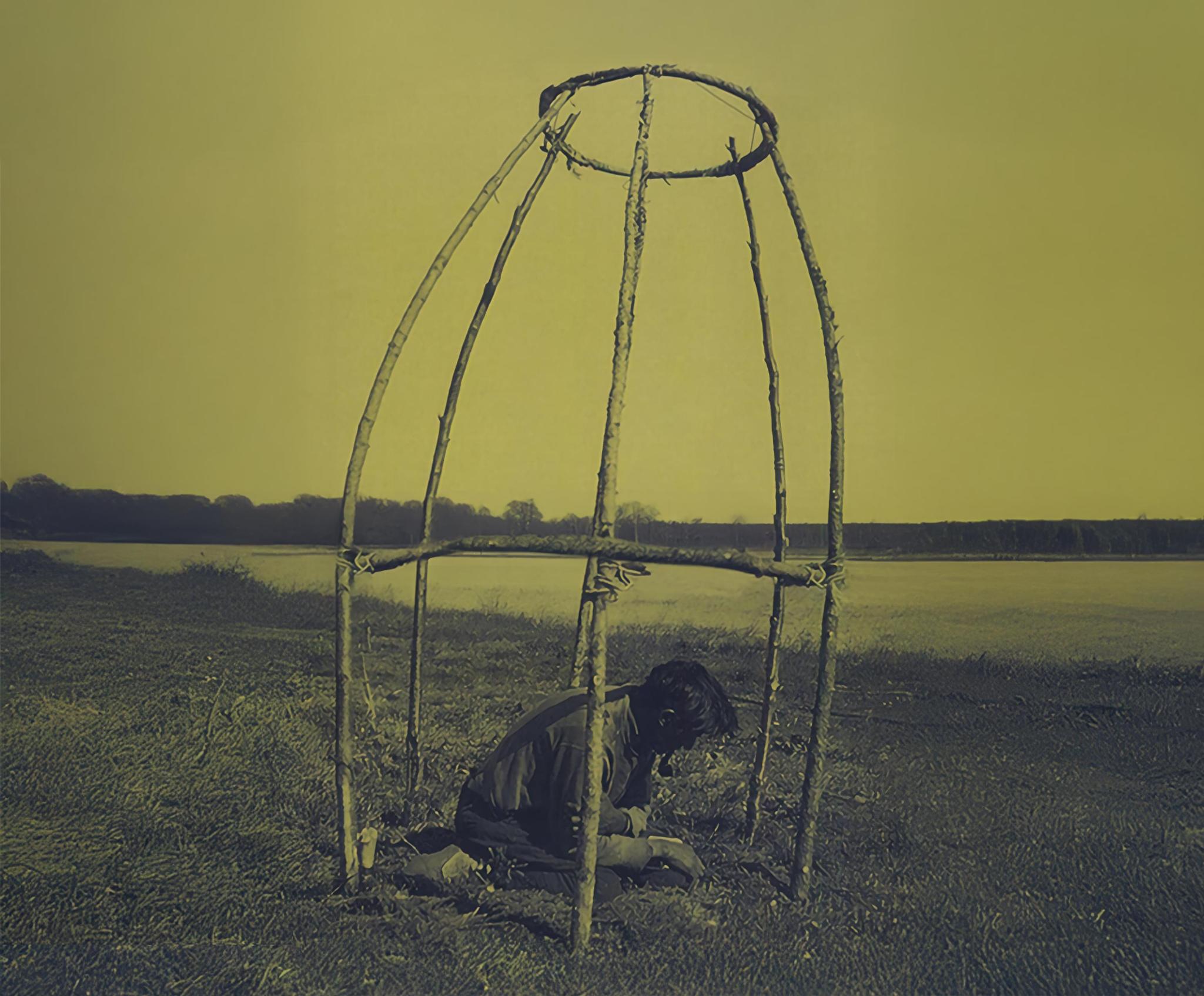 Cree Elder kneeling inside a shake tent or spirit lodge